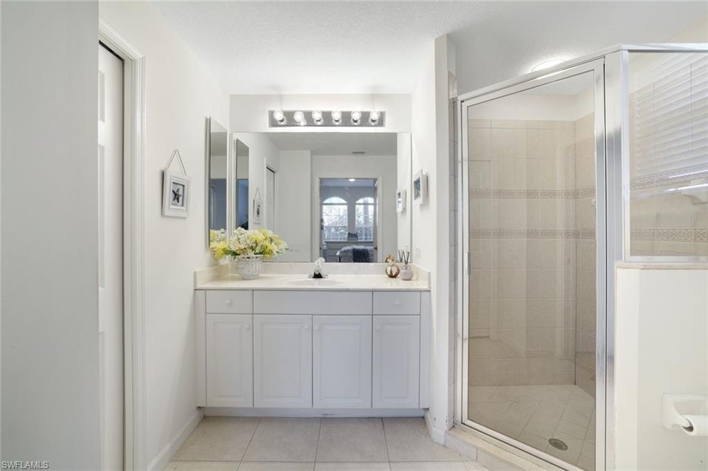 Full bathroom featuring a shower stall, connected bathroom, and light tile patterned flooring