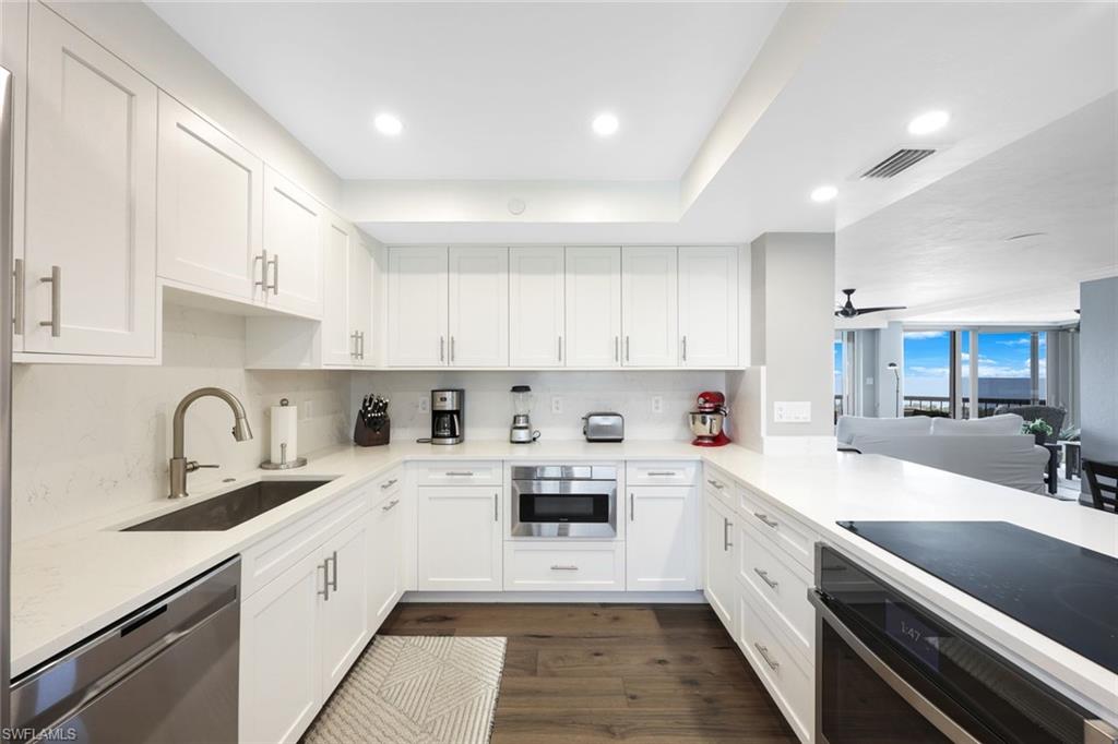 Kitchen with appliances with stainless steel finishes, tasteful backsplash, white cabinets, sink, and dark wood-type flooring