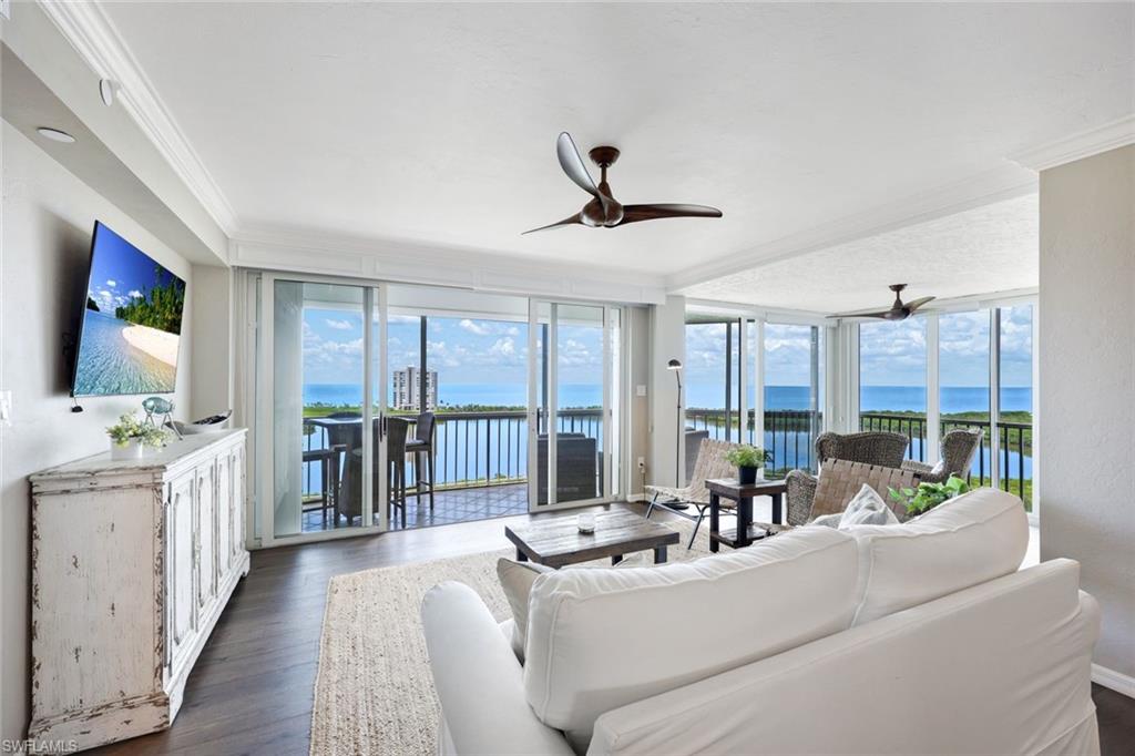 Living room featuring dark hardwood / wood-style floors, a water view, crown molding, and ceiling fan