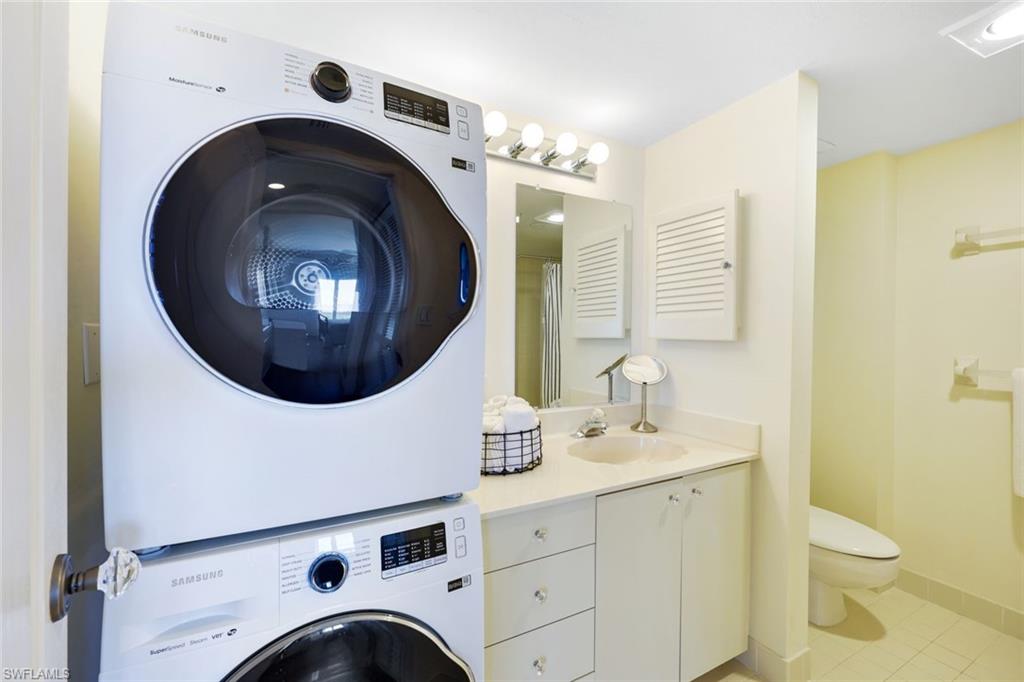 Laundry room with sink, stacked washer and clothes dryer, and light tile patterned floors