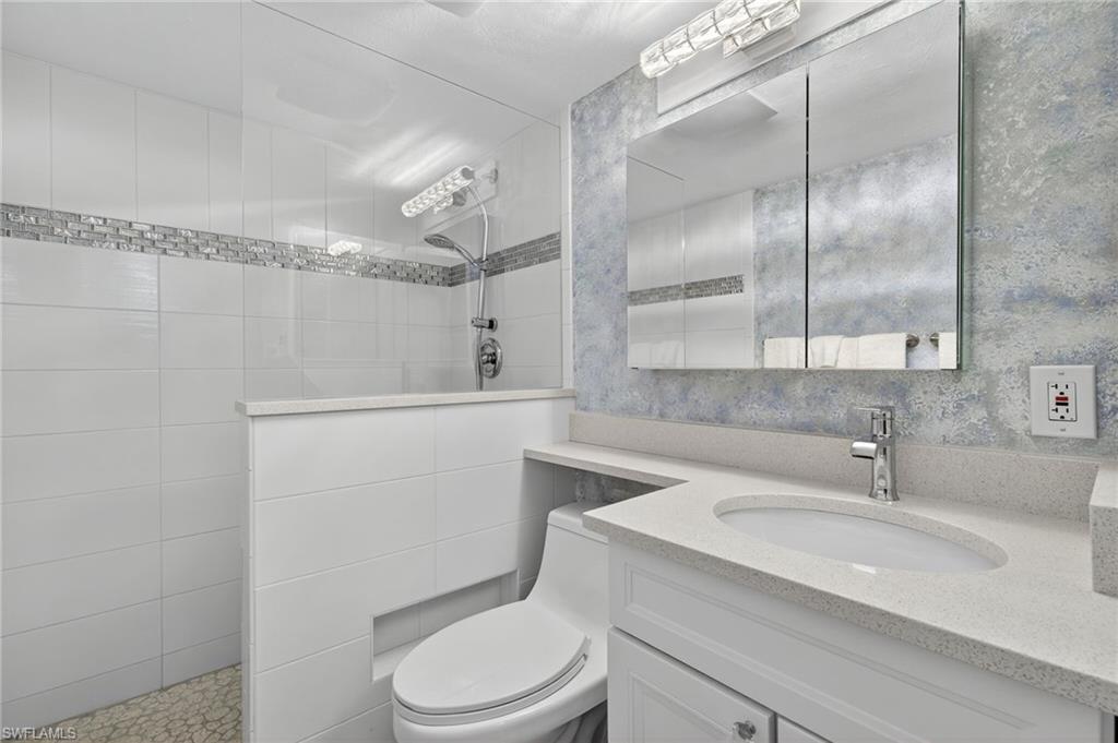 Full bath featuring walk in shower, vanity, and wallpapered walls