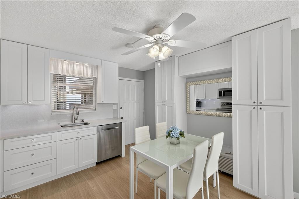 Kitchen featuring white cabinets, light wood-type flooring, appliances with stainless steel finishes, ceiling fan, and a textured ceiling