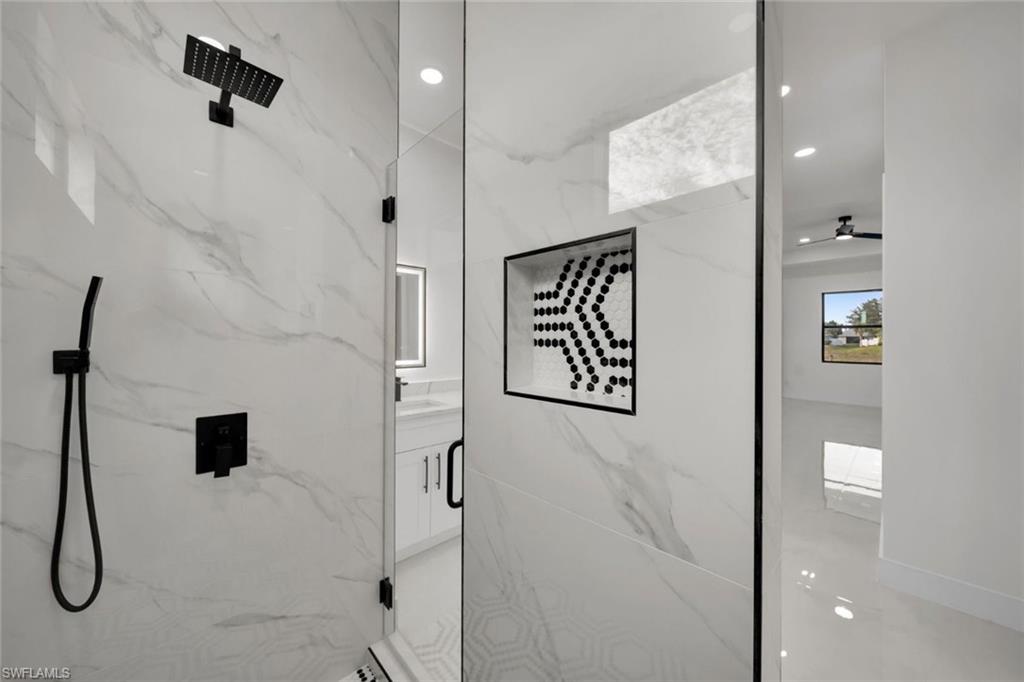 Bathroom with vanity and a marble finish shower