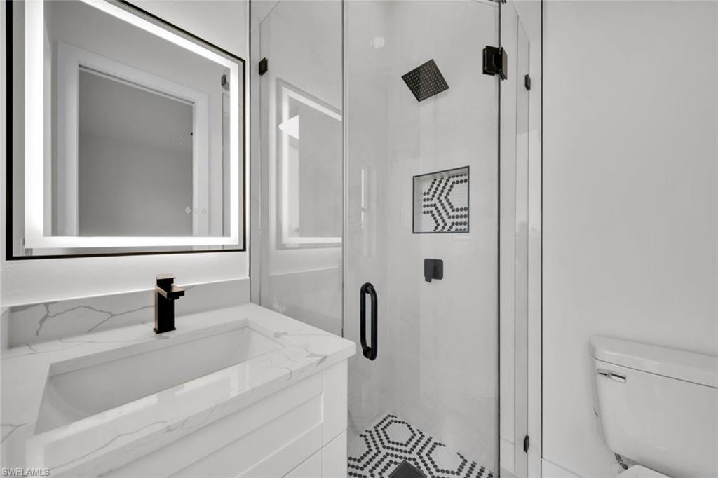 Bathroom with a marble finish shower, double vanity, and recessed lighting