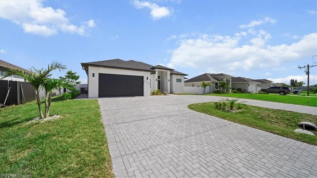 Prairie-style house with decorative driveway, an attached garage, and stucco siding