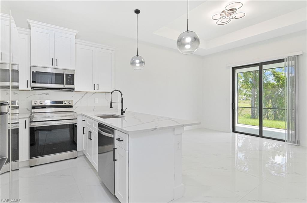 Kitchen with light marble finish floors, white cabinets, appliances with stainless steel finishes, and light stone counters