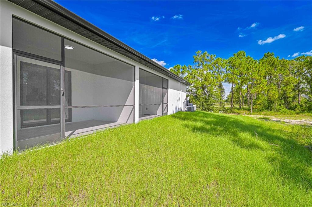 View of grassy yard featuring a sunroom