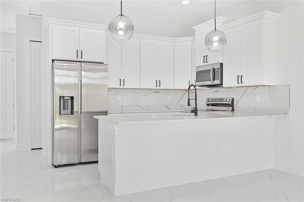 Kitchen featuring tasteful backsplash, white cabinetry, light stone counters, and recessed lighting