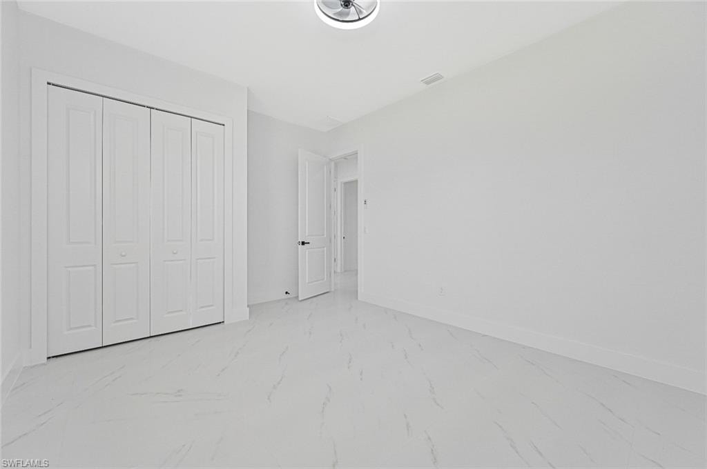 Unfurnished bedroom with a closet and light marble finish floors