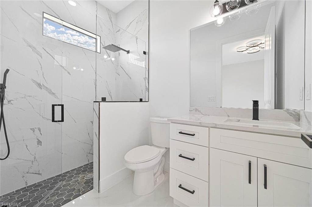 Bathroom featuring a marble finish shower and vanity
