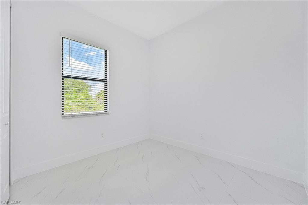 Unfurnished room with baseboards and marble look tiles