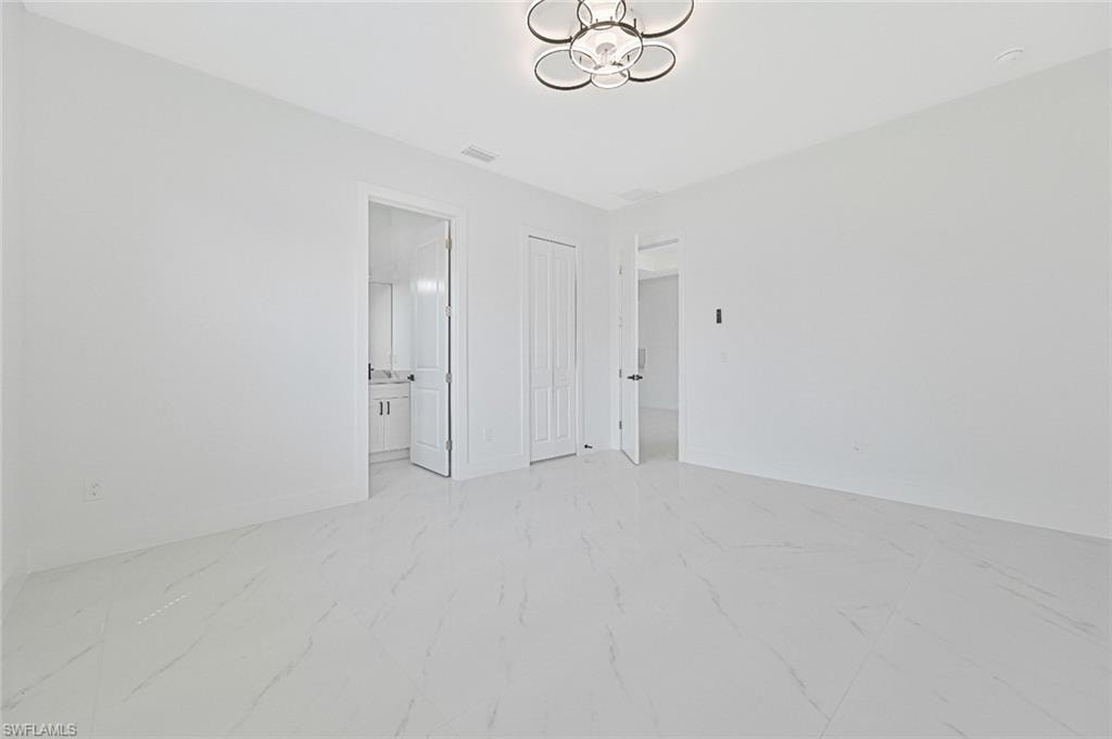 Unfurnished bedroom with light marble finish floors, a closet, and connected bathroom