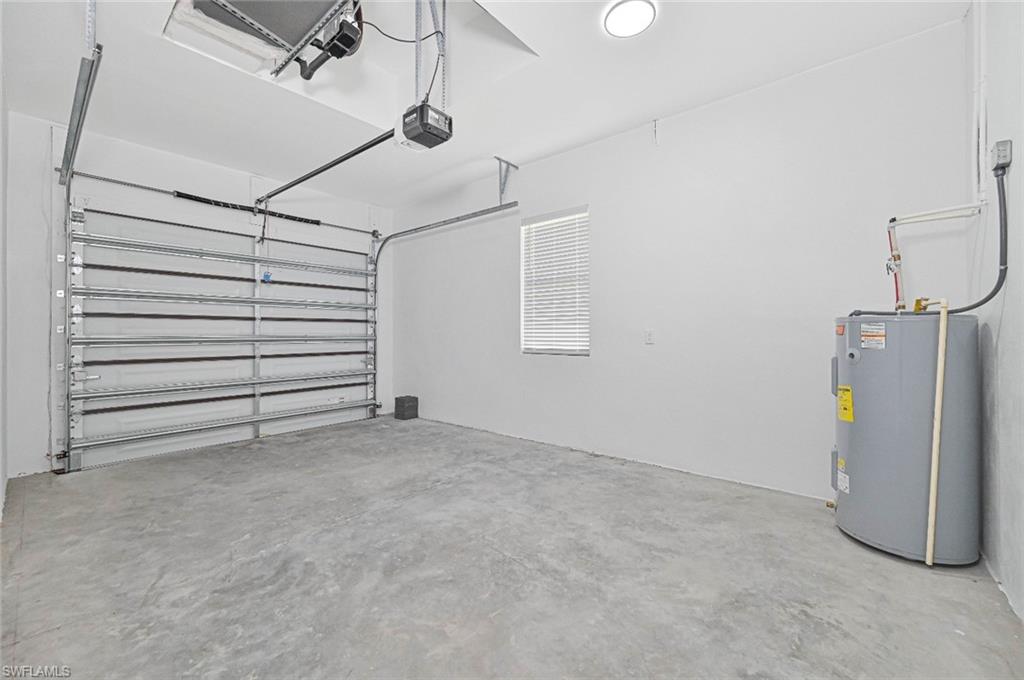 Garage featuring electric water heater and a garage door opener