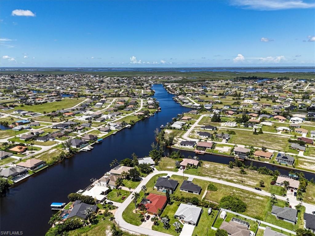 Aerial view of property and surrounding area featuring nearby suburban area and a large body of water