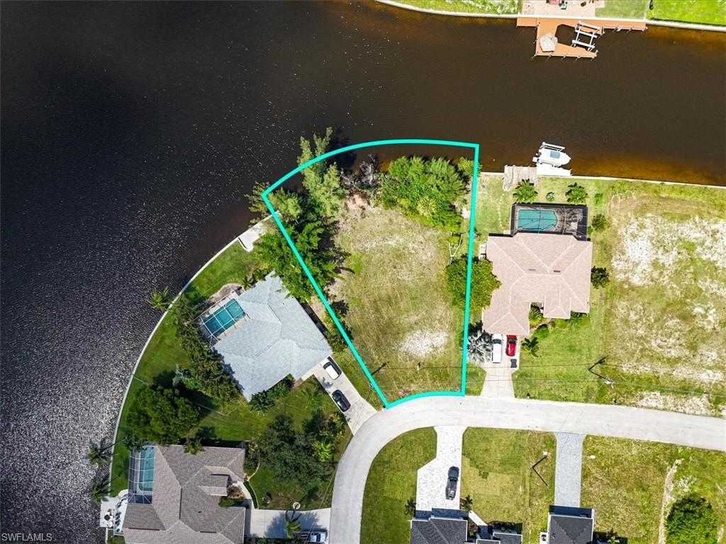 Aerial view of residential area with property parcel outlined and a large body of water