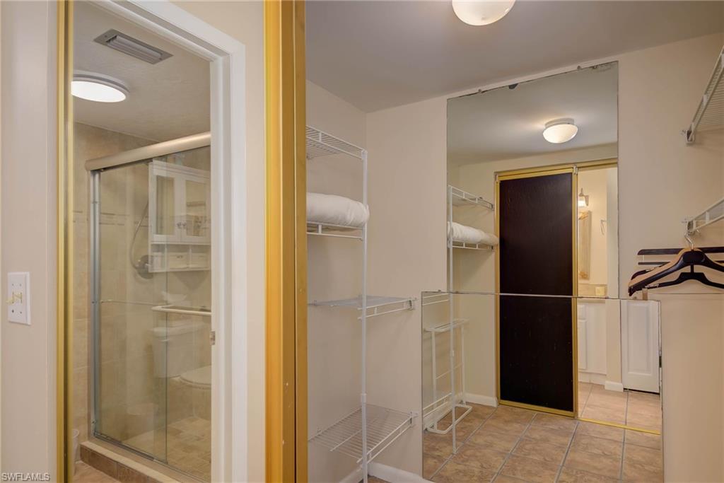 Bathroom with a walk in closet, a shower stall, and light tile patterned floors