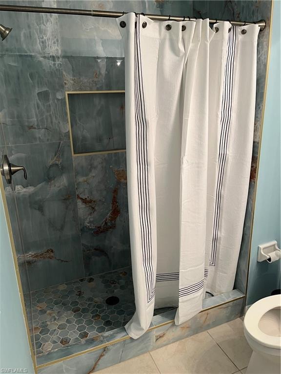 Bathroom featuring toilet, tile patterned floors, and a shower stall