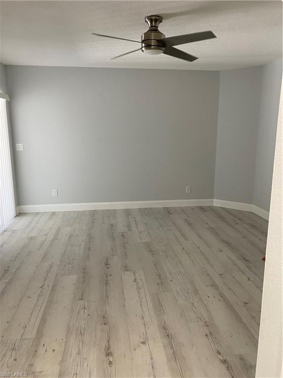 Empty room with a textured ceiling, light wood finished floors, and ceiling fan