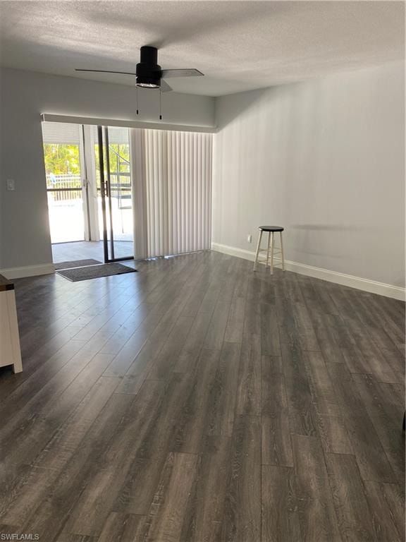 Empty room with a textured ceiling, dark wood-style flooring, and ceiling fan