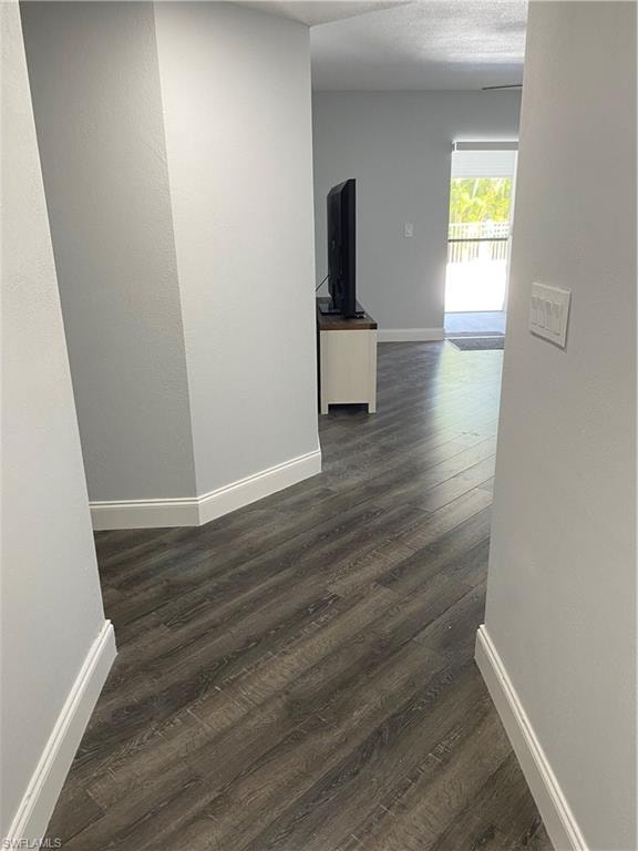 Corridor with dark wood-style floors and a textured wall