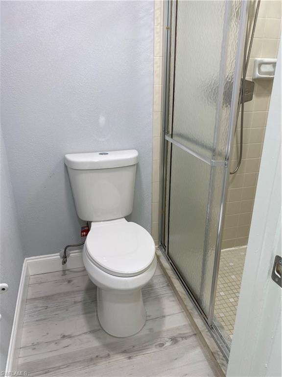 Full bath featuring a stall shower, a textured wall, and light wood-style floors