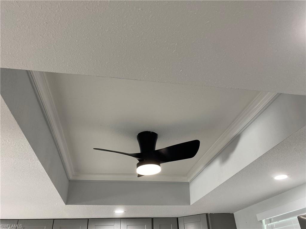 Detailed view of a textured ceiling, ornamental molding, recessed lighting, and ceiling fan