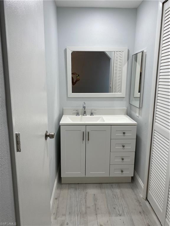 Bathroom with vanity, light wood-style flooring, and a closet
