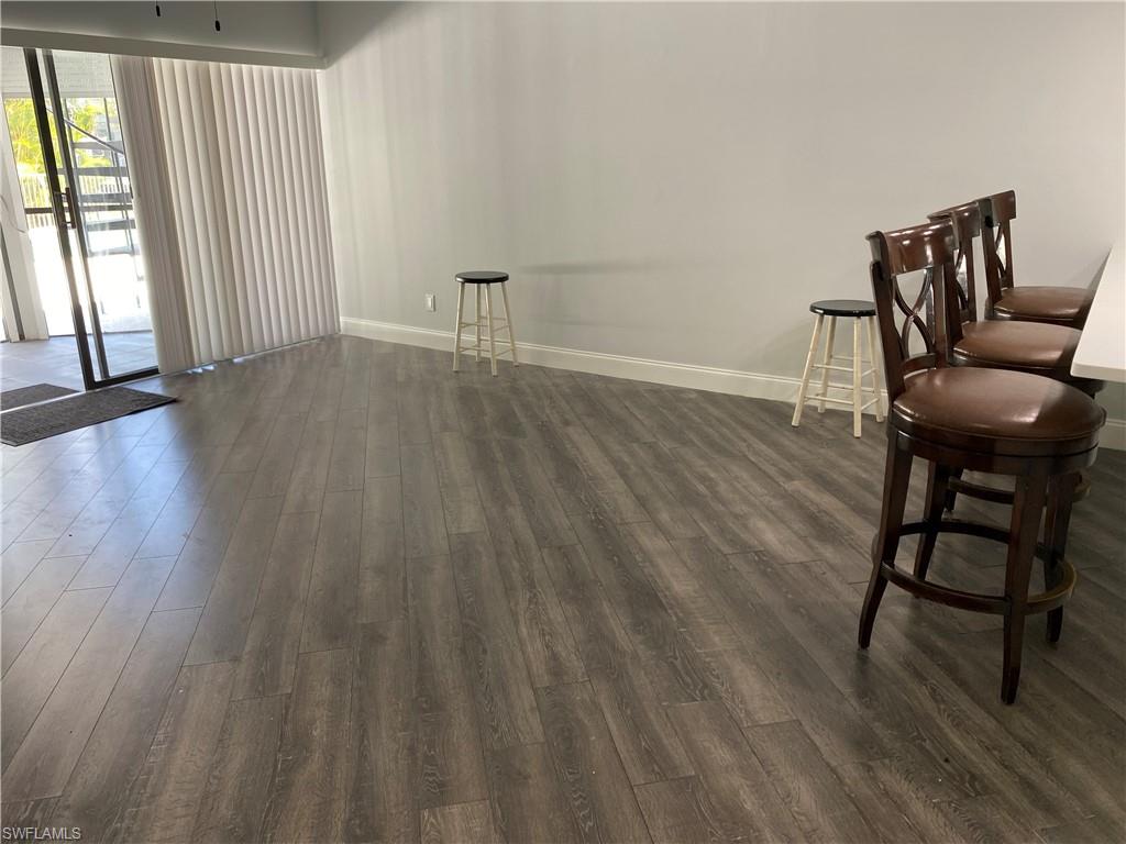 Unfurnished room featuring dark wood-style flooring and baseboards