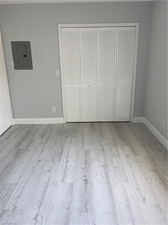 Unfurnished bedroom featuring electric panel, light wood finished floors, and a closet