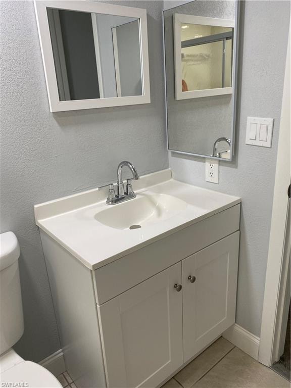Bathroom with a textured wall, vanity, and light tile patterned floors