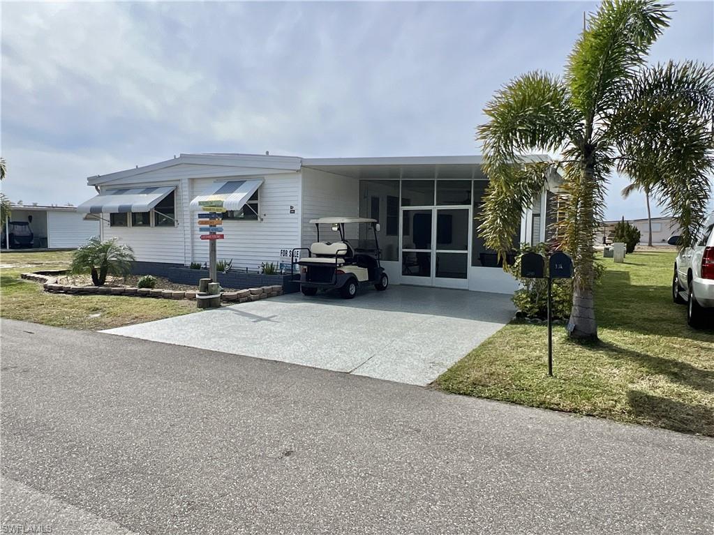 View of front of home with a front lawn, concrete/epoxy driveway, lanai, and a carport