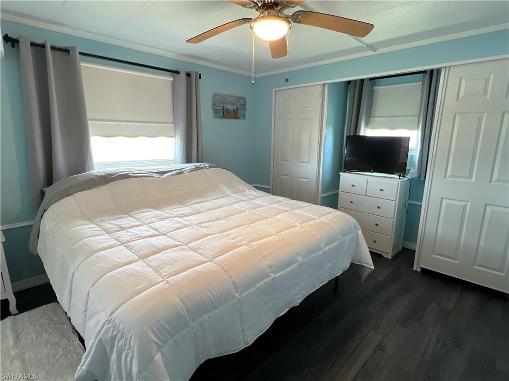 Bedroom with king sized bed, multiple closets, dark wood-style vinyl floors, and ceiling fan. Has air/heat pump on wall for comfort.