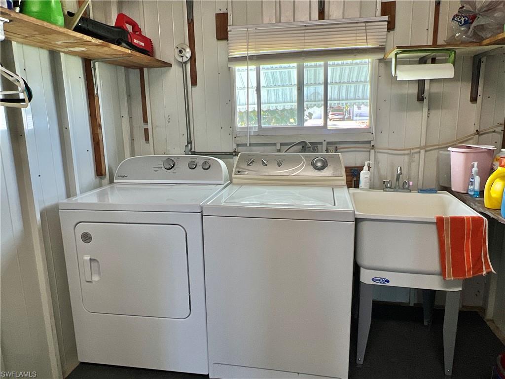 Washroom featuring washer and dryer, Hot water tank, utility sink and shelving for extra storage.