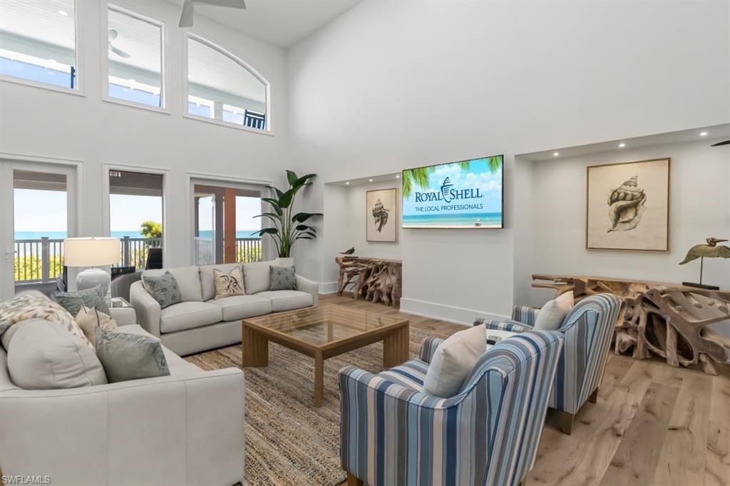 Living area featuring wood finished floors, a towering ceiling, and recessed lighting