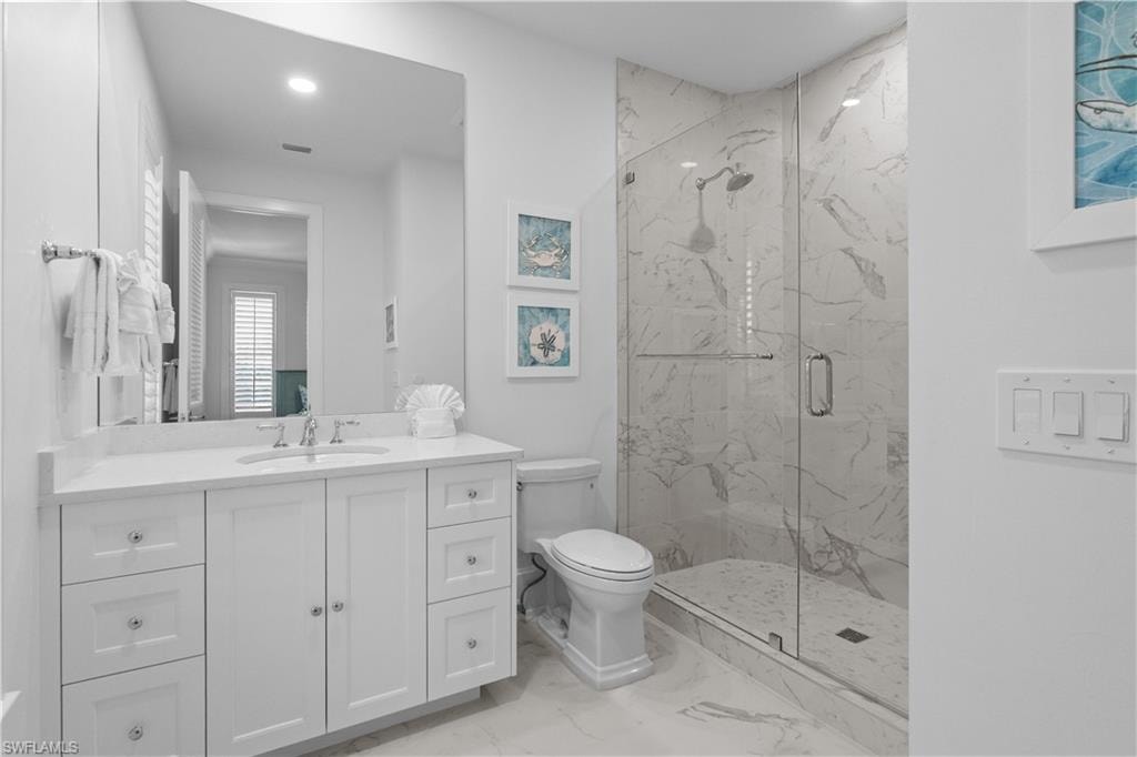 Bathroom with a marble finish shower, vanity, and light marble finish floors
