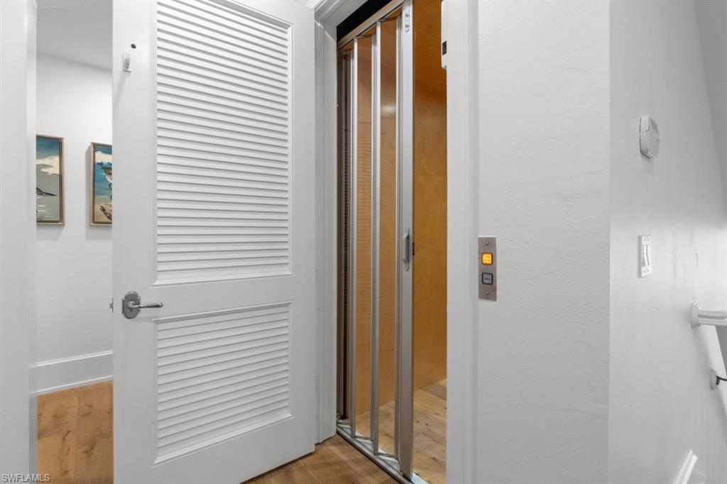 Corridor with wood finished floors and elevator