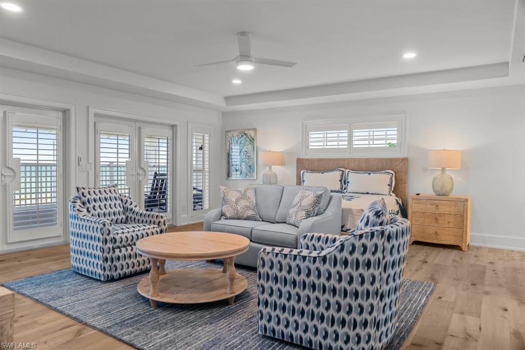 Bedroom with a raised ceiling, light wood-style floors, access to exterior, recessed lighting, and a ceiling fan