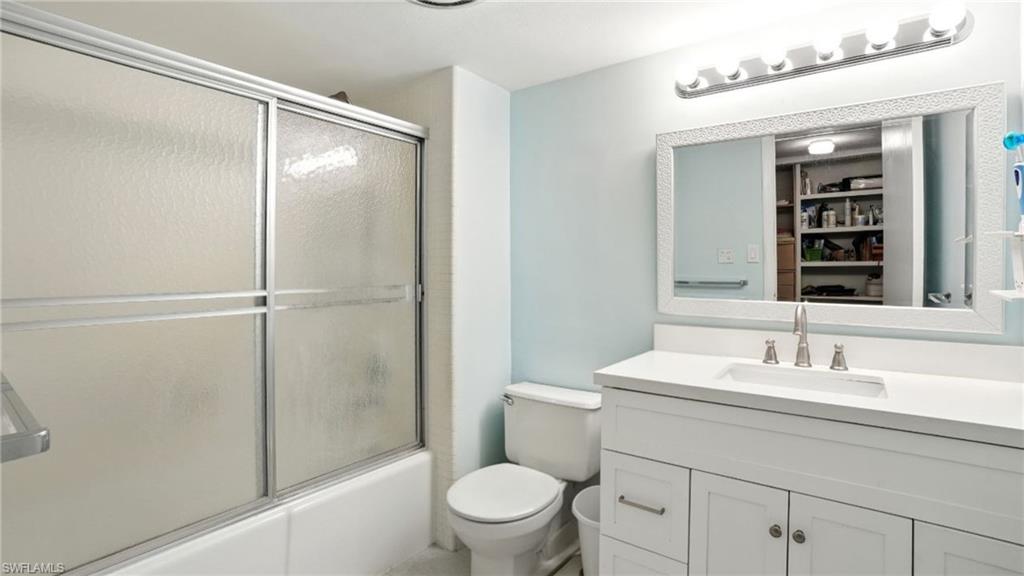 Bathroom featuring vanity, bath / shower combo with glass door, and a closet - Virtually Edited Image
