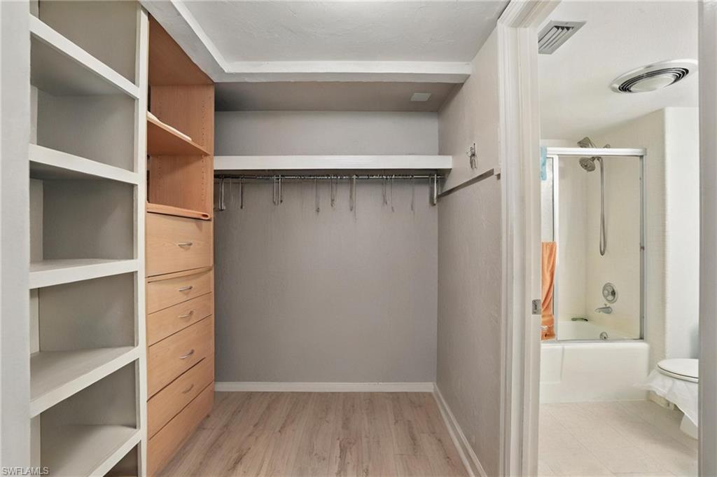 Walk in closet featuring light wood finished floors - Virtually Edited Image