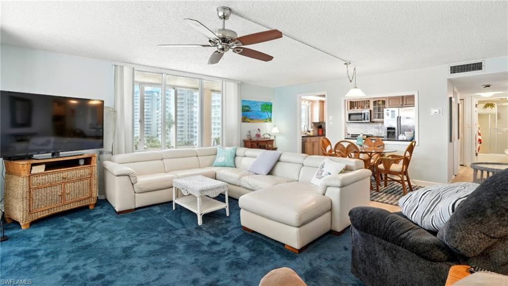 Living room featuring a textured ceiling, ceiling fan, and carpet floors - Virtually Edited Image