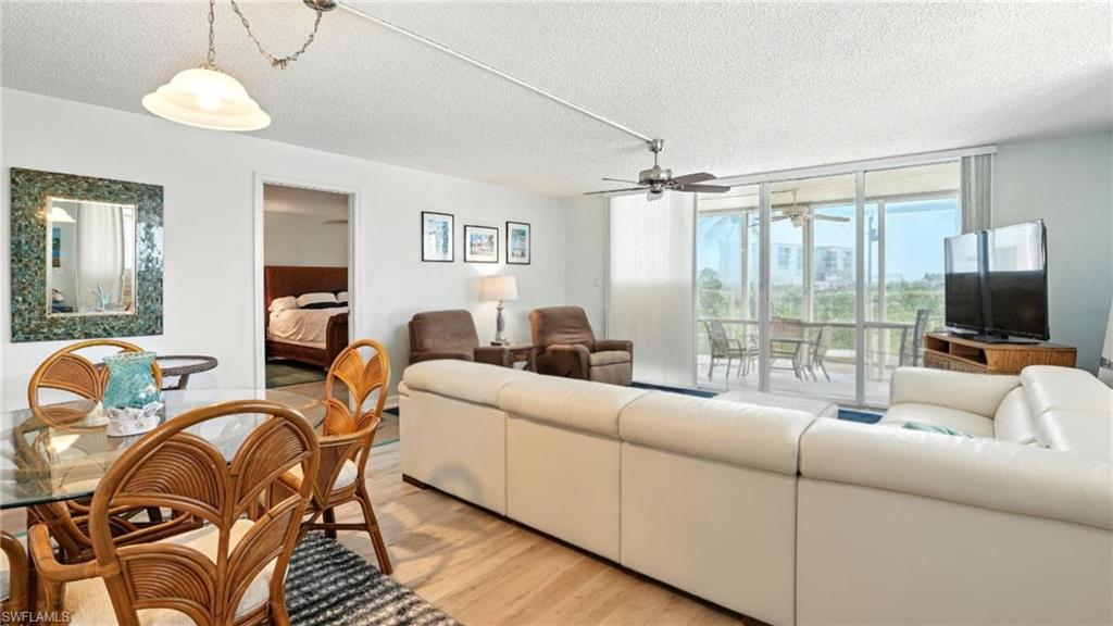 Living room featuring a textured ceiling, light wood-style floors, and expansive windows - Virtually Edited Image