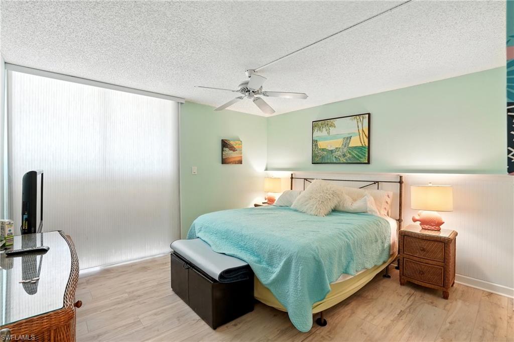 Bedroom with wood finished floors, a textured ceiling, and a ceiling fan - Virtually Edited Image