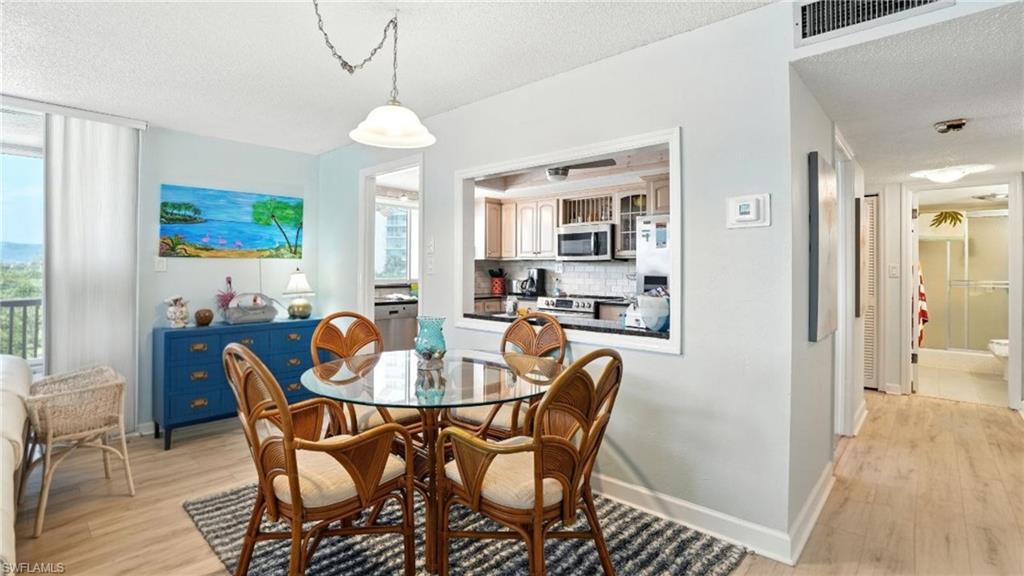Dining room with a textured ceiling and light wood-style flooring - Virtually Edited Image