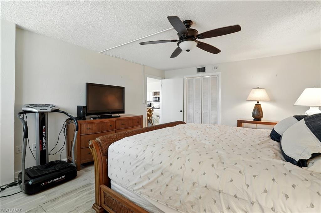 Bedroom featuring a closet, a textured ceiling, light wood-style floors, and a ceiling fan - Virtually Edited Image