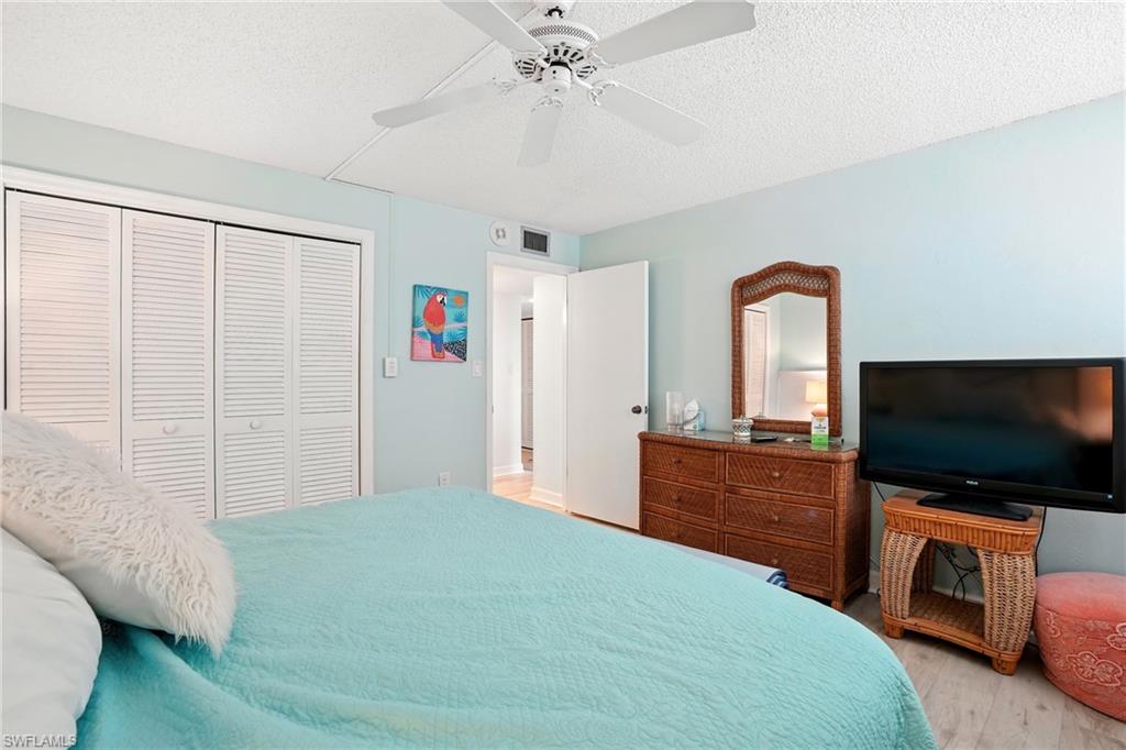 Bedroom with a textured ceiling, a closet, wood finished floors, and ceiling fan - Virtually Edited Image