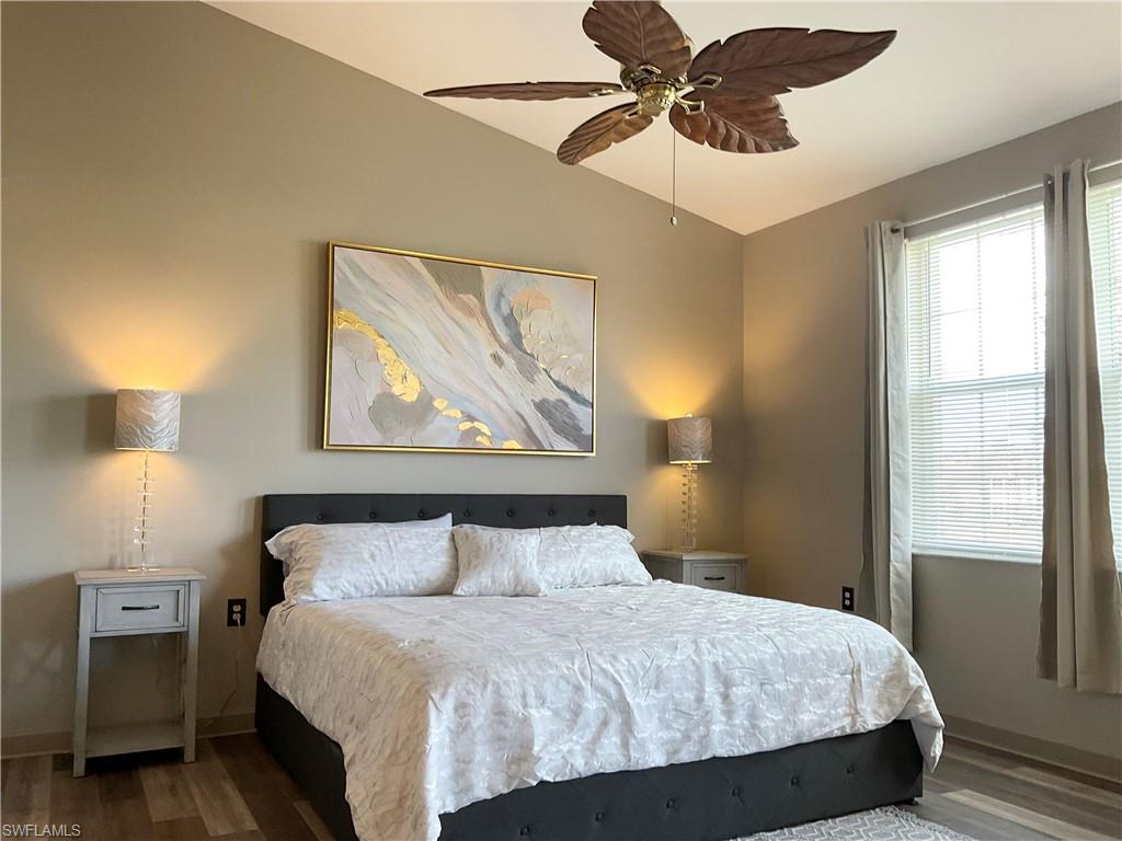 Primary Bedroom featuring king bed, ceiling fan, wood-style flooring, and lofted ceiling.  View of lake and opens to lanai area.