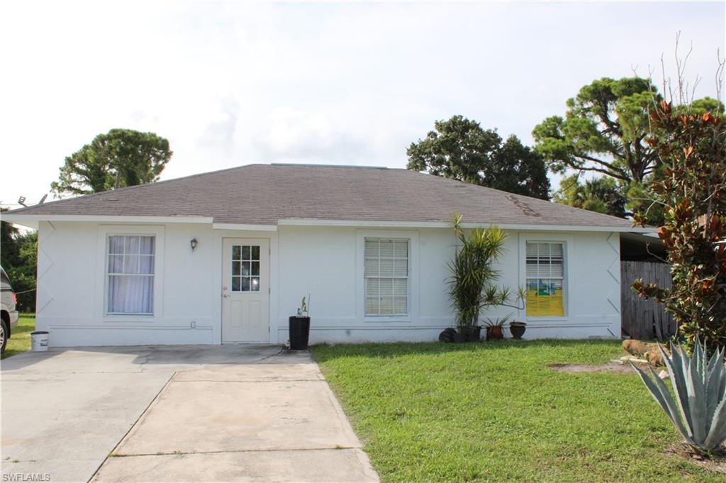 Ranch-style home featuring a front yard, concrete driveway, roof with shingles, and stucco siding