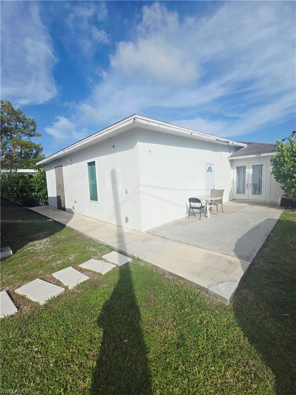 Back of property with a patio, stucco siding, and a lawn