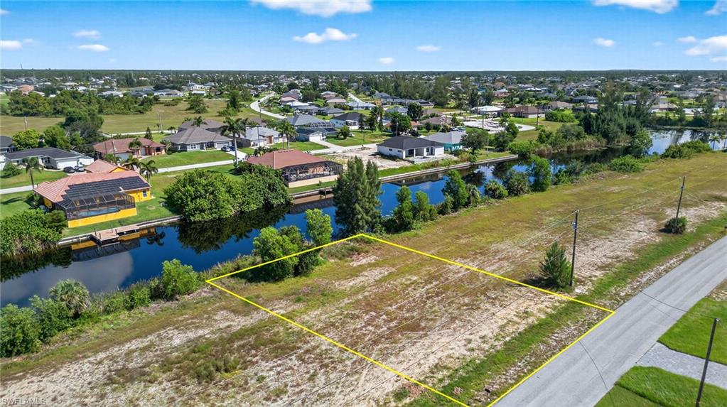 Aerial perspective of suburban area with a nearby body of water and property boundaries highlighted