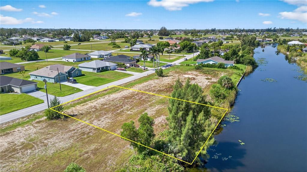 Aerial perspective of suburban area featuring property parcel outlined and a nearby body of water